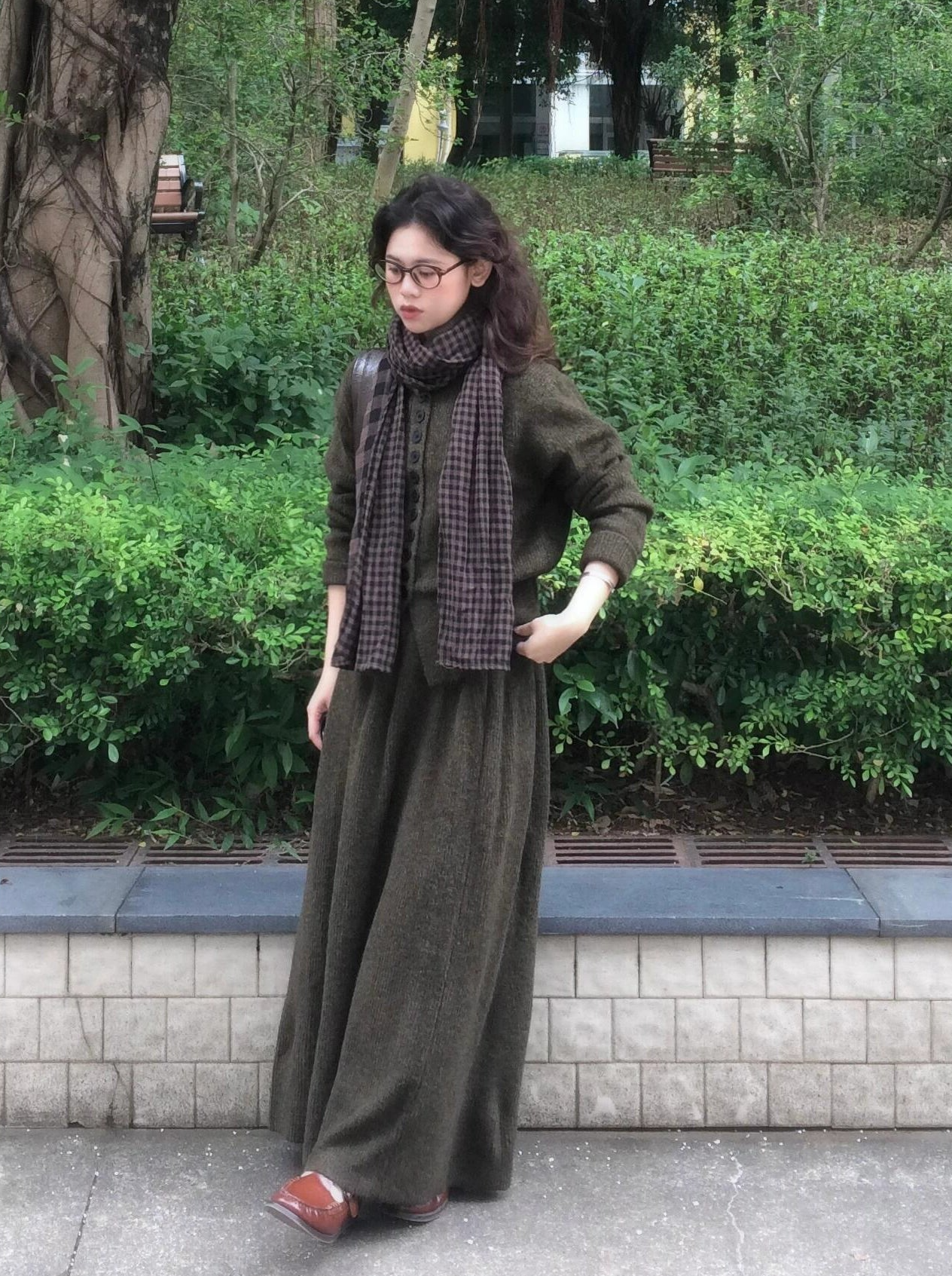 a woman standing on a sidewalk in a long dress